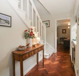 A hallway with a staircase and a console table at St. Marys House in Church Westcote near Bledington