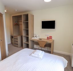 A bedroom with a bed, wardrobe, desk, and TV at Eamont Park First-floor Double Bedroom in Penrith