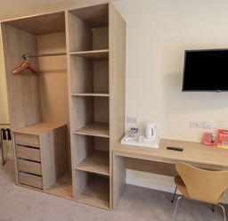 A bedroom with a wardrobe, table, chair, and television at Eamont Park First-floor Double Bedroom in Penrith