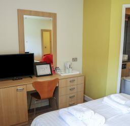 A bedroom with a desk, television, and bathroom at Bedroom 7 in Penrith