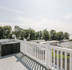A deck with an outdoor storage container and a view of mobile homes at Number 42 in Wemyss Bay