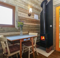 A dining area with a table and wood stove at Shepherd Hut’s in Bristol