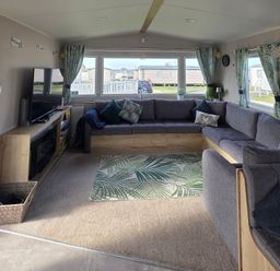 A living room with a sofa and television at Pines 15 in Porthcawl