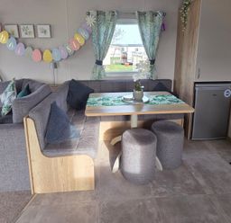 A living room with a sofa, table, and refrigerator at Pines 15 Porthcawl