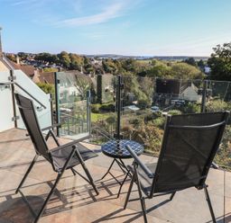 A balcony with chairs and a table overlooking a view at 10 Brython Place Tenby