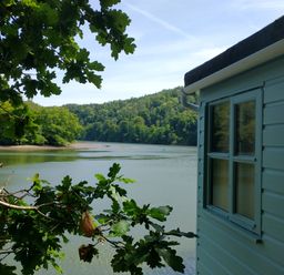 A view of water and trees from the side of a building at The Sharpham Boat House in Ashprington