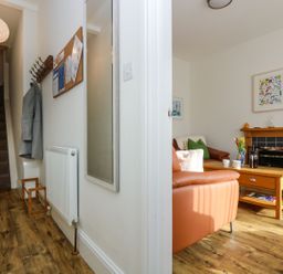 An entryway with stairs and coat hooks leading to a living room with a fireplace and leather sofas at Breakers Point in St Ives