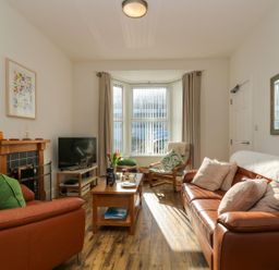 A living room with leather sofas a wooden coffee table a television a fireplace and a window with vertical blinds at Breakers Point in St Ives