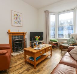 A living room with brown leather sofas a wooden coffee table and a fireplace at Breakers Point in St Ives