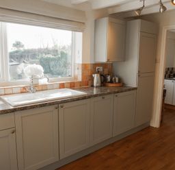 A kitchen with cabinets and sink at Rhianfa Newborough