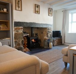 A living room with a fireplace and sofa at Rhianfa in Newborough
