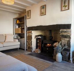 A living room with a fireplace and sofa at Rhianfa in Newborough