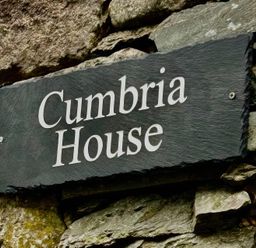 A sign for Cumbria House on a stone wall at Cumbria house