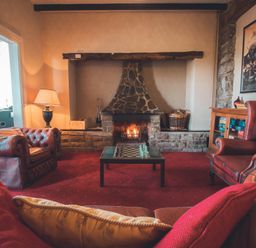 A living room with a fireplace and chairs at Noddfa Country House in Harlech