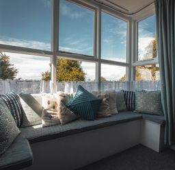 A snug with a sofa and cushions at Noddfa Country House in Harlech