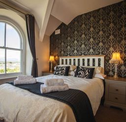 A bedroom with a bed and window at Noddfa Country House in Harlech