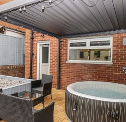 An outdoor area with a hot tub and seating at Milana Tiverton