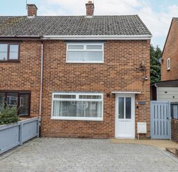 A brick house with windows and a driveway at Milana in Tiverton