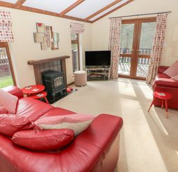 A living room with a red sofa and armchair at Riverside Lodge 3