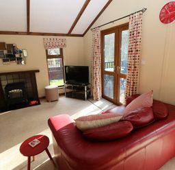 A living room with a sofa and television at Riverside Lodge 3