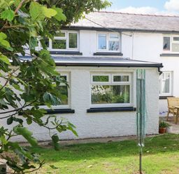 A garden with a house and furniture at Coach House Cottage in 