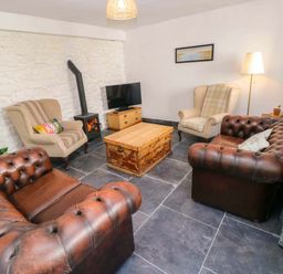 A living room with a coffee table and sofas at Coach House Cottage