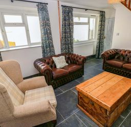 A living room with leather sofas and a wooden coffee table at Coach House Cottage 