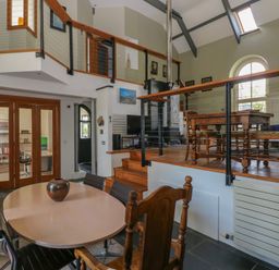 A split-level room with dining tables and chairs wooden railing and a staircase at Zoar Chapel in Carew