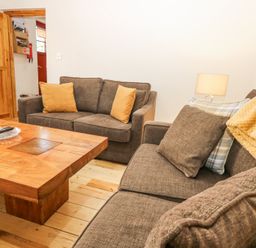 A living room with brown sofas wooden coffee table and a lamp at Smiddy Bothy in Edzell