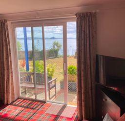 A living room with a view of the garden and sea at 1 Penrose Court in Penzance