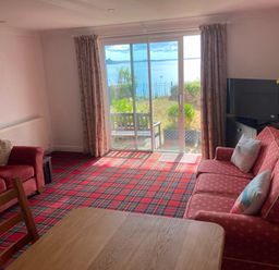 A living room with a sofa, dining table, and television at 1 Penrose Court in Penzance