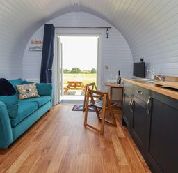An indoor area with a sofa and kitchen unit at Honeypot Hideaways - Acacia
