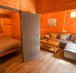A living room with a door, sofa, and table at Stumps Cross Lodge in Upper Coscombe near Winchcombe