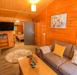 A living room with a sofa and television at Stumps Cross Lodge Upper Coscombe near Winchcombe