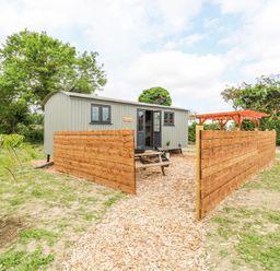 A small shed like building with wooden fencing and a picnic table outside at Woodpecker in Lode near Bottisham