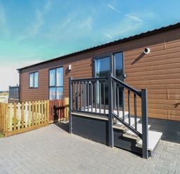 A mobile home with steps and a fence at Sand & Serenity in Bacton