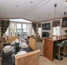 A living room with a dining area and kitchen counter at Ty Seren in New Quay