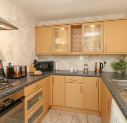 A kitchen with wooden cabinets toaster microwave and sink at Old Malthouse Apartment Weymouth