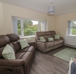 A living room with recliner sofas and a coffee table at Glandwr House in Crossgates near Llandrindod Wells