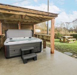 A hot tub under a wooden shelter in an outdoor area at Glandwr House Crossgates near Llandrindod Wells