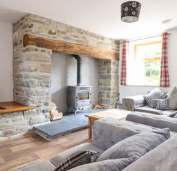 A living room with a wood stove and sofa at Gwernffridd
