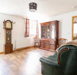 A living room with a clock and a cabinet at Gwernffridd