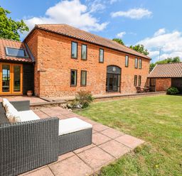 A house with a patio and a sofa at Lakeside Barn Aylsham