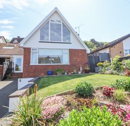 A house with a sloped roof flower beds and a lawn at 67 Pendre Avenue Prestatyn