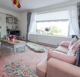A living room with a pink sofa and floral carpet at 67 Pendre Avenue in Prestatyn