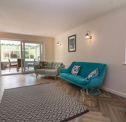 A living room with two sofas a glass door leading to a dining area and a patterned rug at Hillside in Bishops Cleeve
