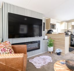A living room with a television and kitchen area at Number 34 Foxburrow Hang in Great Yarmouth