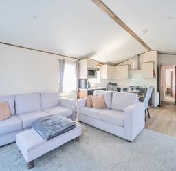 A living area with two sofas, an ottoman, and a kitchen with dining table and chairs at Lakeside Lullaby - Billing Aquadrome