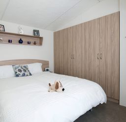 A bedroom with a bed and wardrobe at Mariner's Meadow - Hayling Island