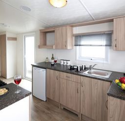 A kitchen with a sink, stove, refrigerator, and fruit bowl at Mariner's Meadow - Hayling Island